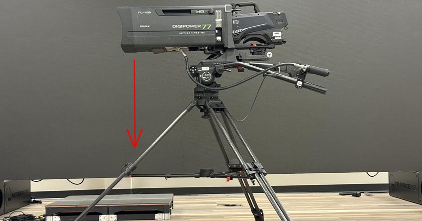 camera-lens-long-glass-balanced-over-tripod-leg